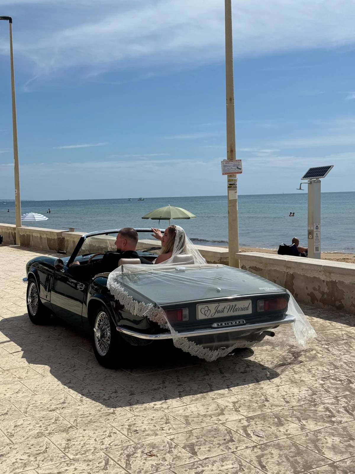 Una coppia di sposi nella Triumph Spitfire aperta, davanti al mare